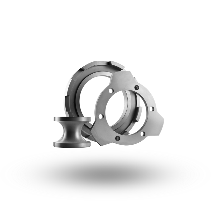 Drei metallische Bauteile, darunter ein zylindrisches Teil und zwei ringförmige Komponenten mit Löchern und Einkerbungen.